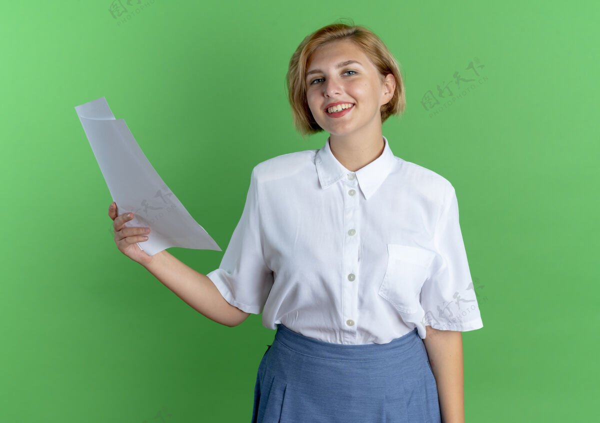 被单年轻的微笑着的金发俄罗斯女孩拿着纸页孤立的绿色背景与复制空间年轻金发微笑