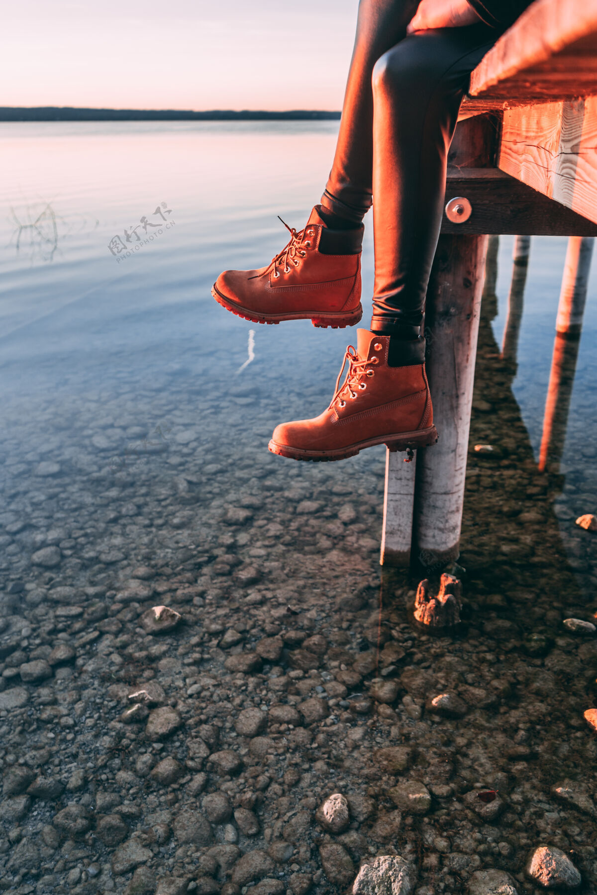 冷静坐在湖边木制人行道上的女人腿湖石头