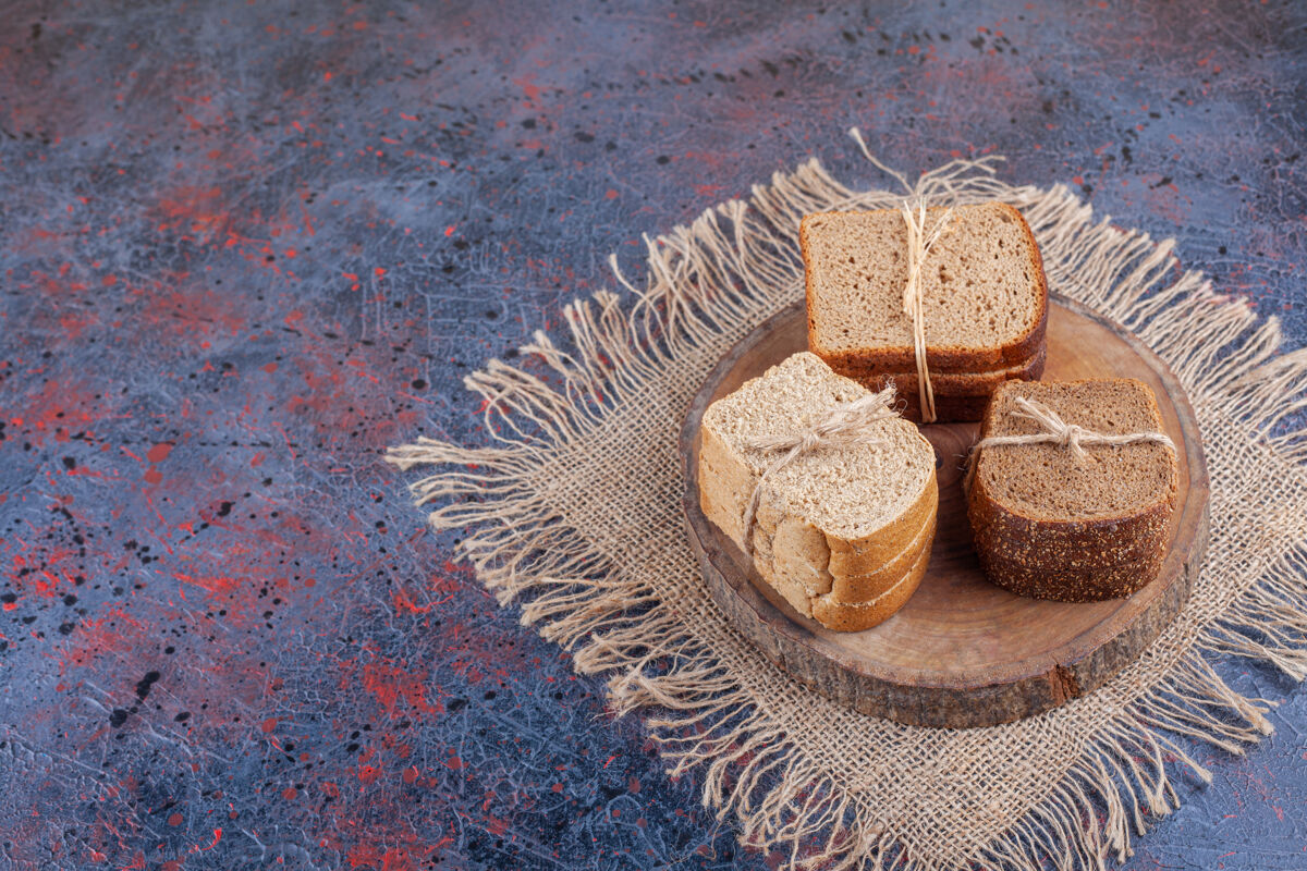 面包皮一堆切片面包放在一块粗麻布餐巾的木板上 蓝色的美味堆面团
