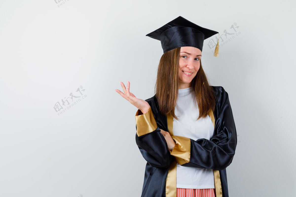 学校女毕业生身着制服举手摆姿势的肖像 休闲服 迷人的前景色大学Cap妇女