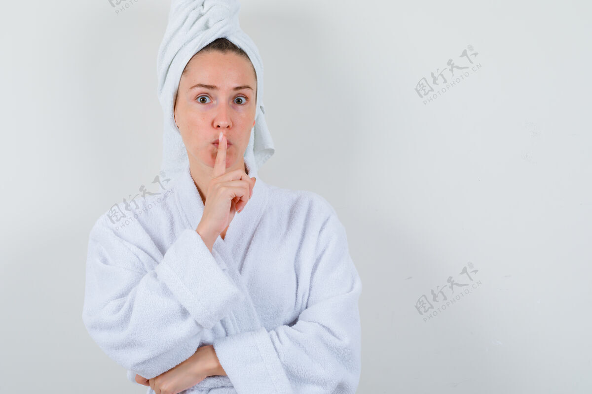 人年轻的女士在白色浴衣 毛巾和显示沉默的姿态仔细看 前视图皮肤女孩人