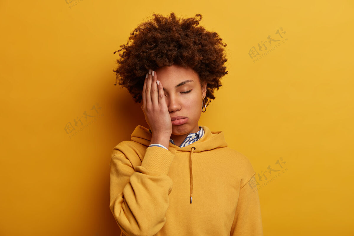连帽衫疲惫不堪的美国黑人妇女捂着半张脸 整天疲惫不堪地练习考试 有着过度劳累的表情迟到失眠无聊