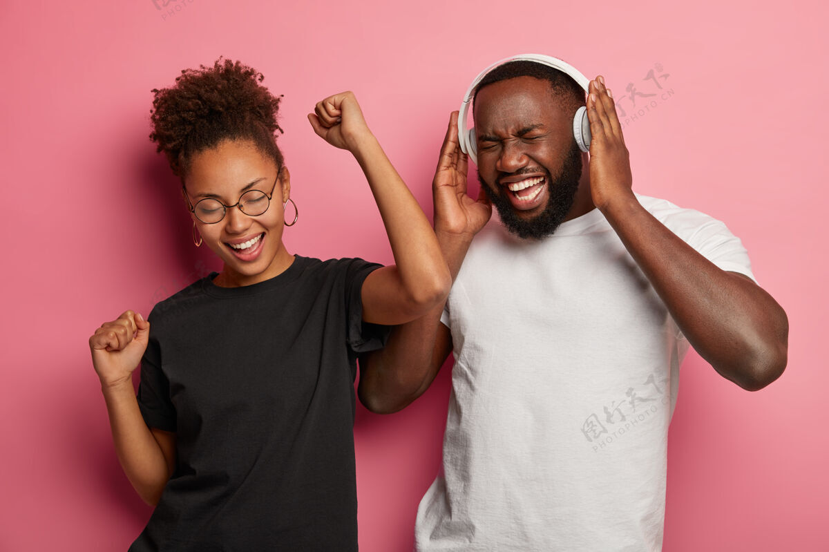 眼镜快乐的非洲裔美国夫妇的照片有乐趣和跳舞大声音乐 庆祝顺利通过考试环节 使用耳机无忧无虑声音情侣