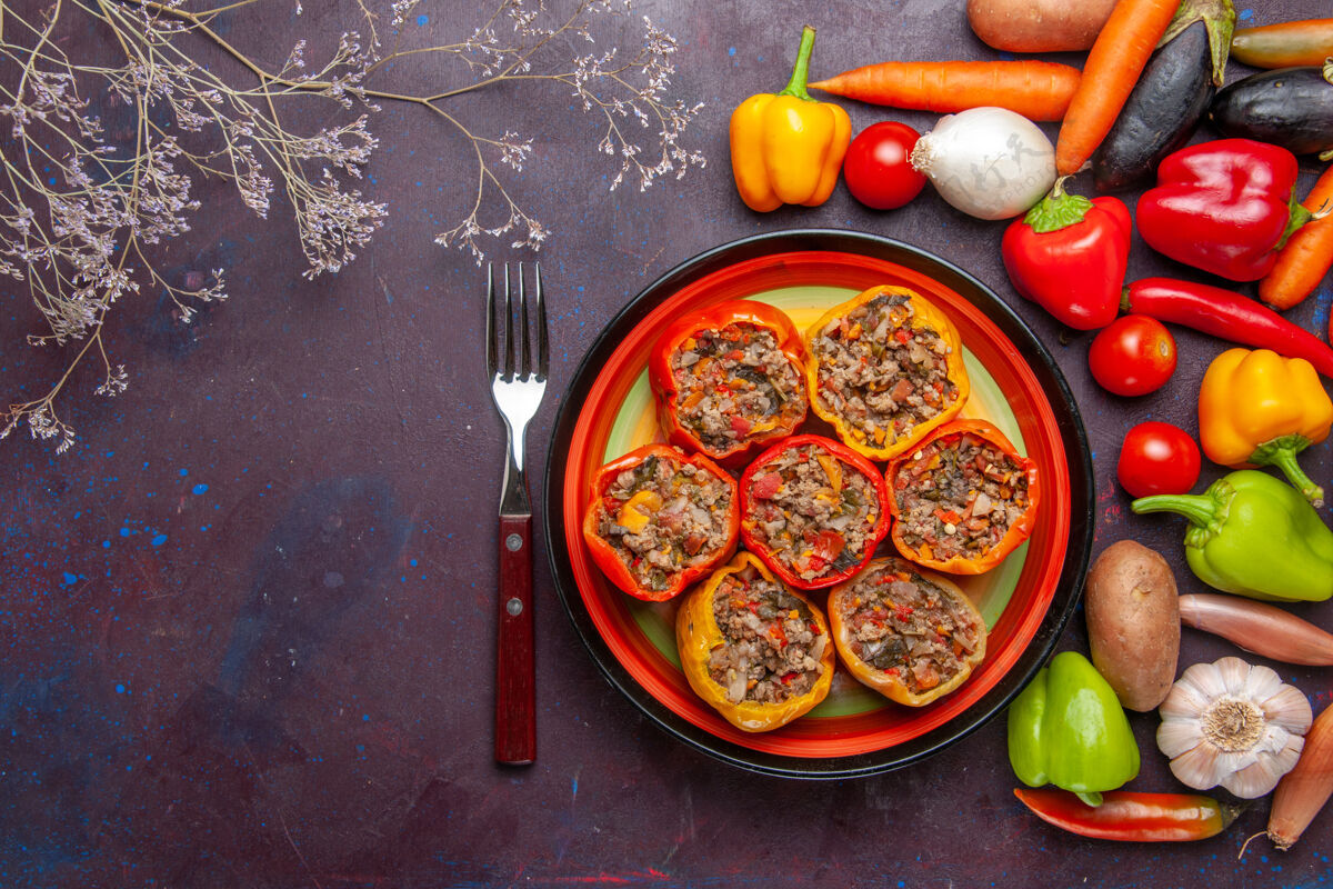 膳食顶视图熟甜椒与不同的调味料对深灰色的表面食物多尔玛蔬菜餐牛肉午餐晚餐顶部