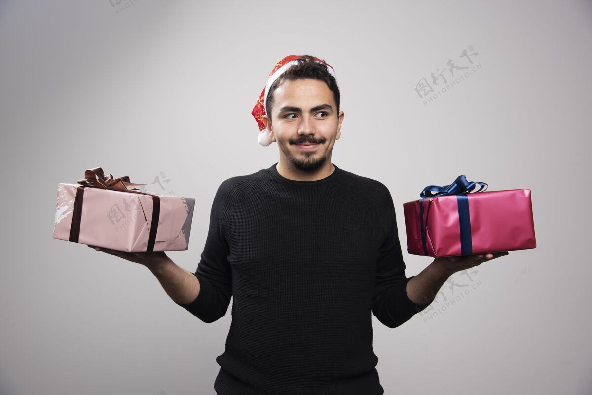 男性一个戴着圣诞老人帽子的笑脸男人 手里拿着新年礼物肖像情感男人