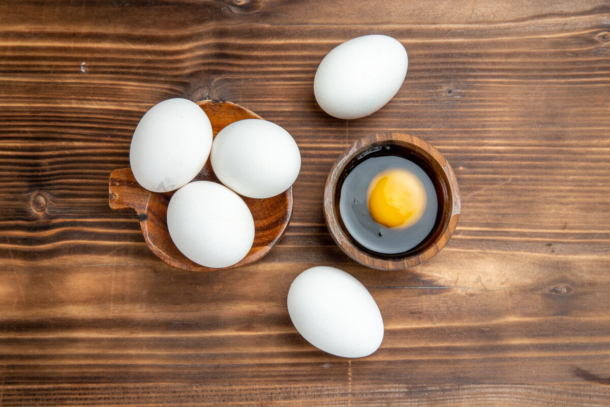 配料俯视整个生鸡蛋在棕色的木制表面上用餐早餐木制鸡蛋鸡肉景观膳食