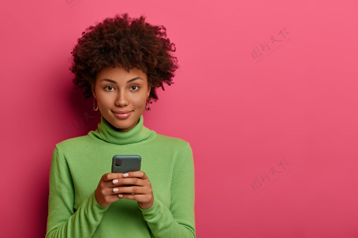 美国漂亮的黑人发型女人在智能手机上留言 浏览网络 自信地看着相机空白用户姿势