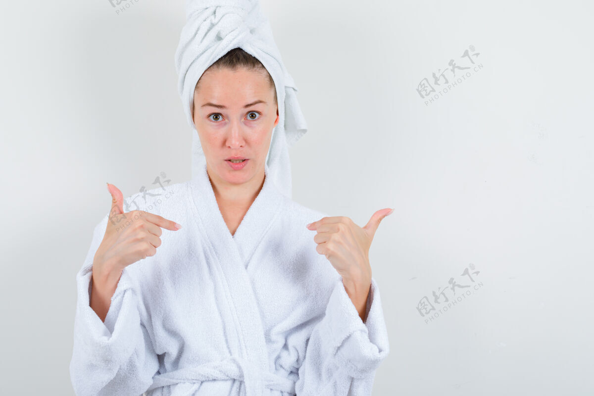 健康年轻的女士指着自己在白色浴袍 毛巾 看起来犹豫不决前视图魅力自然人