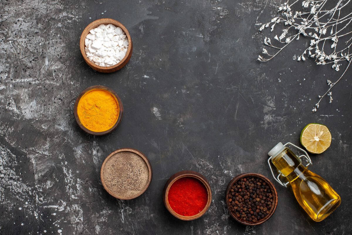 香料顶视图不同的调味品用深色的油上桌 香料颜色的胡椒粉黑胡椒油生意