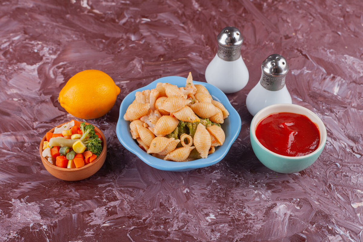 香料意大利贝壳面食配番茄酱和混合蔬菜沙拉 放在浅色桌上番茄贝壳酱汁