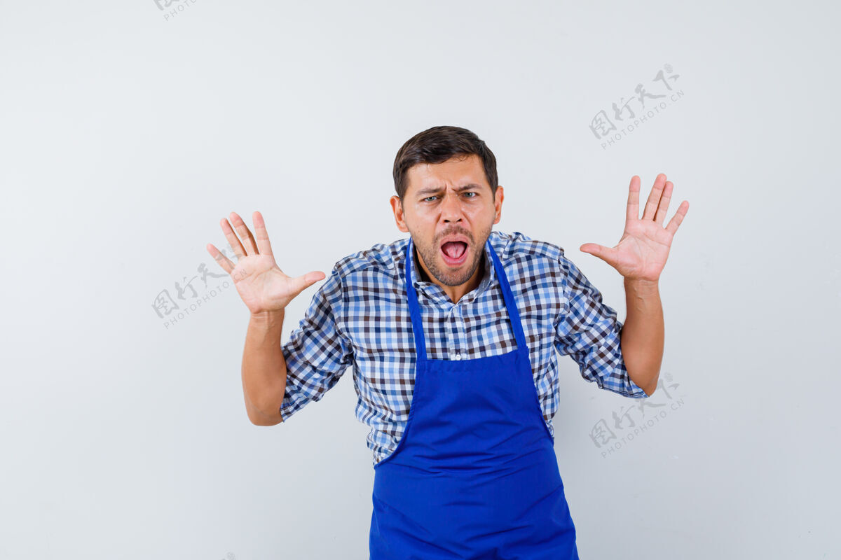 成人穿着蓝色围裙和衬衫的年轻男厨师男士男士烹饪
