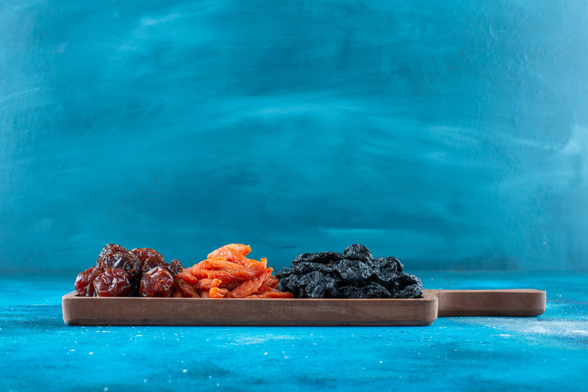 有机把干李子和杏子放在蓝色的木板上营养水果板