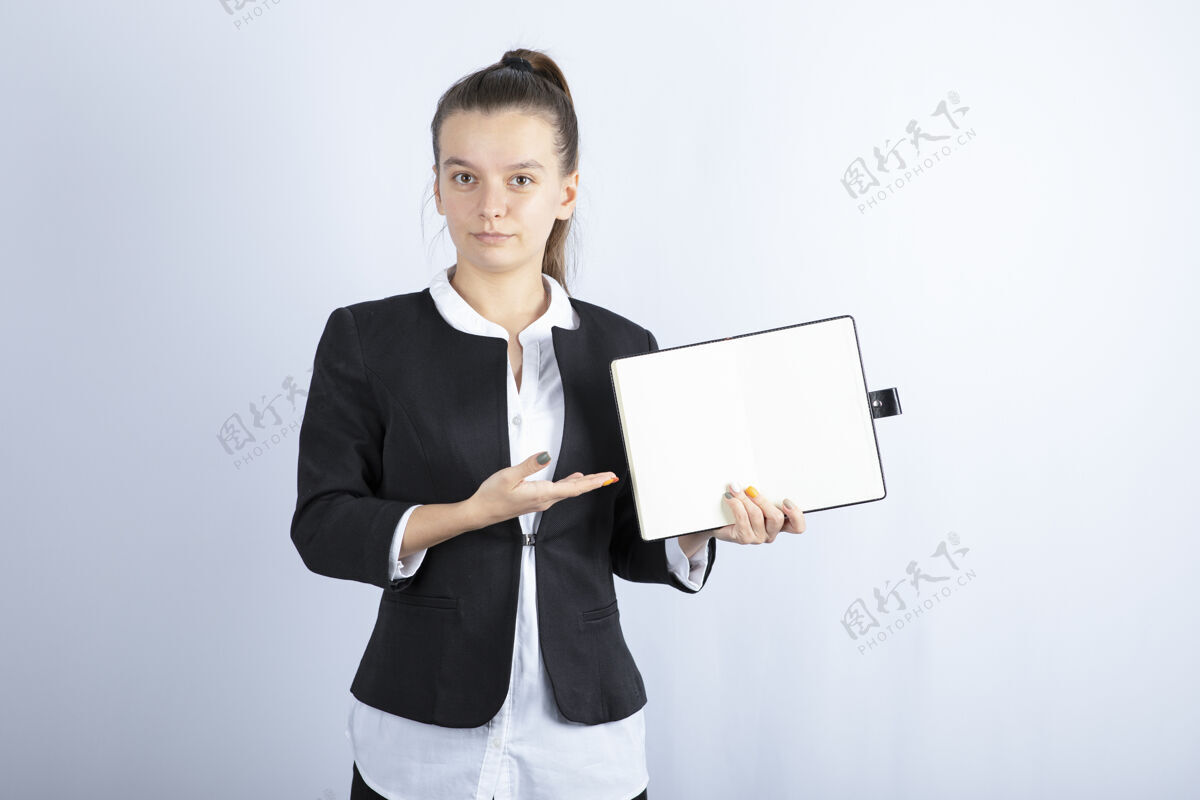 女性年轻女教师指着白色背景笔记本的画像高质量照片女孩年轻人女人