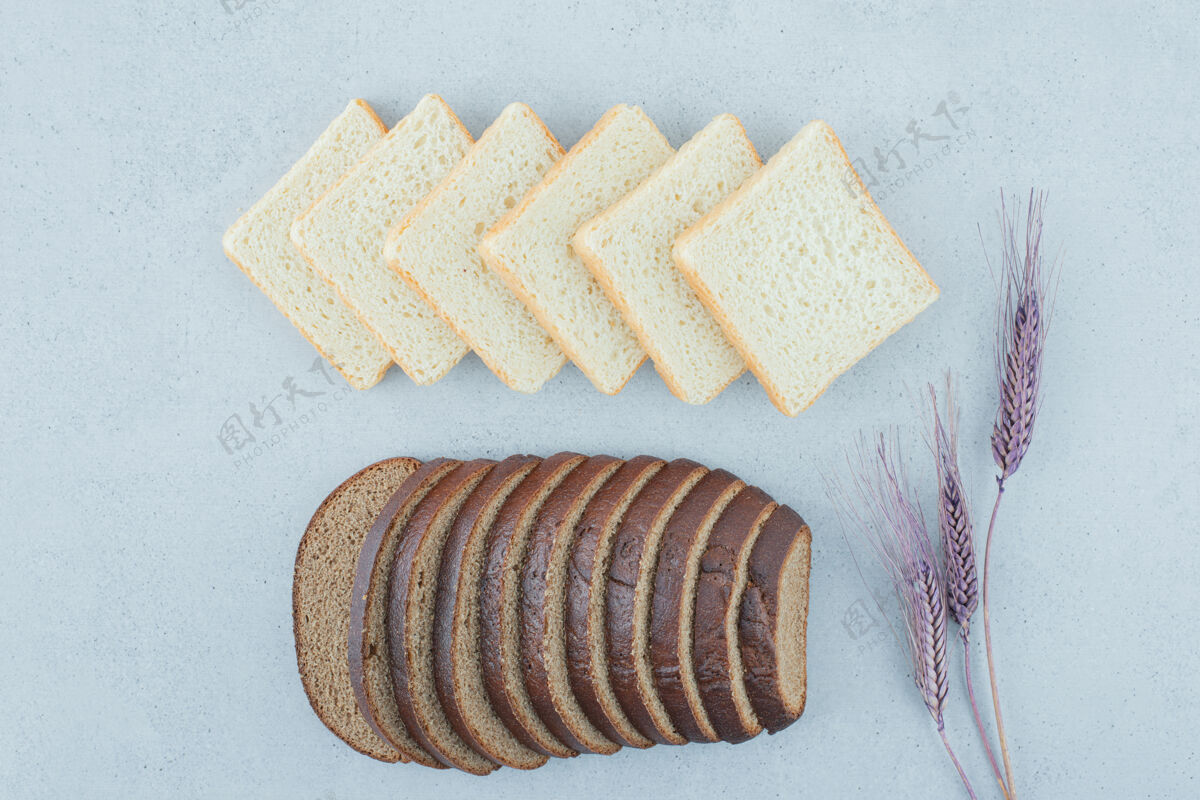 黑麦烤面包和黑面包片放在石头表面和小麦美味不同顶视图