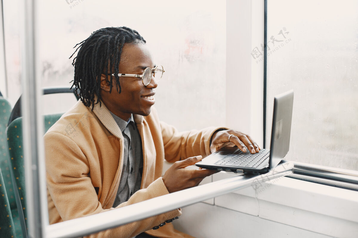 美国人一个非洲裔美国人坐在城市公共汽车上一个穿棕色外套的人一个拿着笔记本电脑的人成人年轻人公众