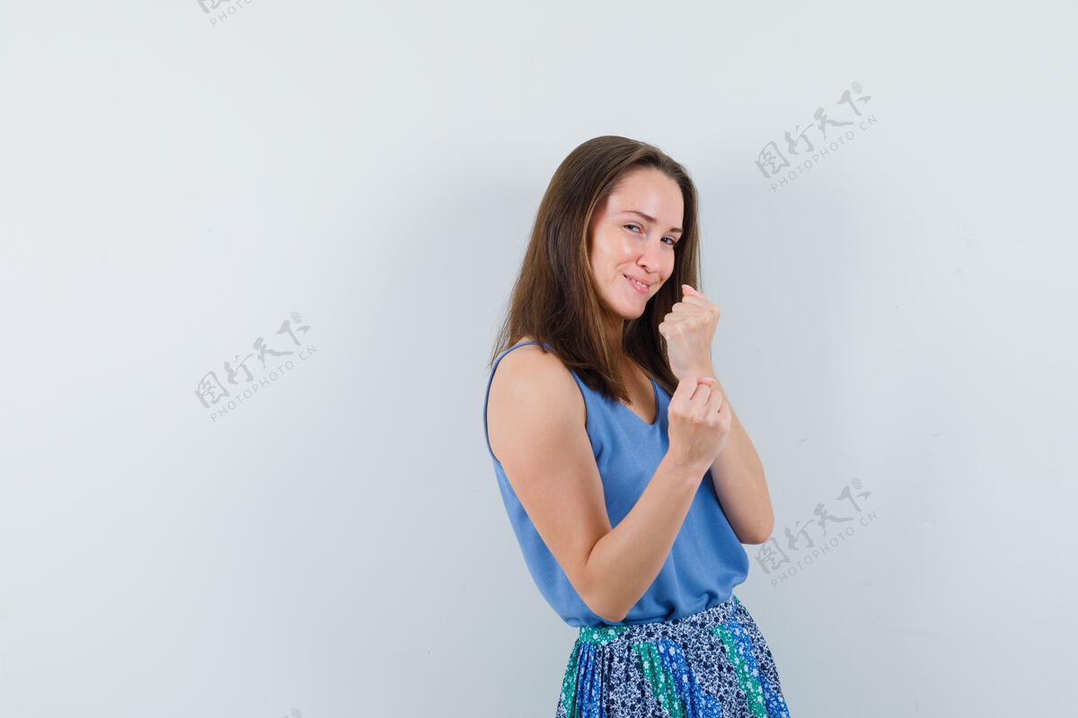 黑发年轻的女士站在一个拳击姿势在单身 裙子和看起来高兴头发水疗姿势