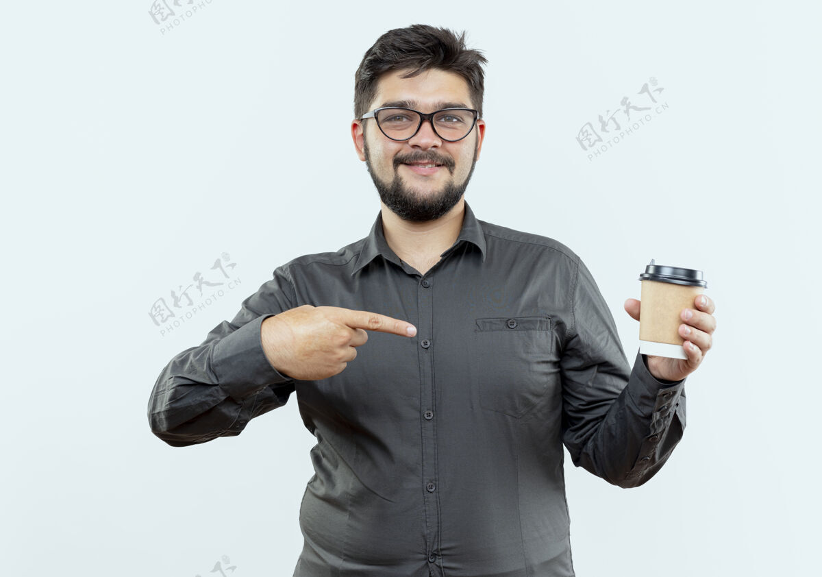 杯子高兴的年轻商人戴着眼镜拿着咖啡杯指着白色的背景请眼镜商务人士