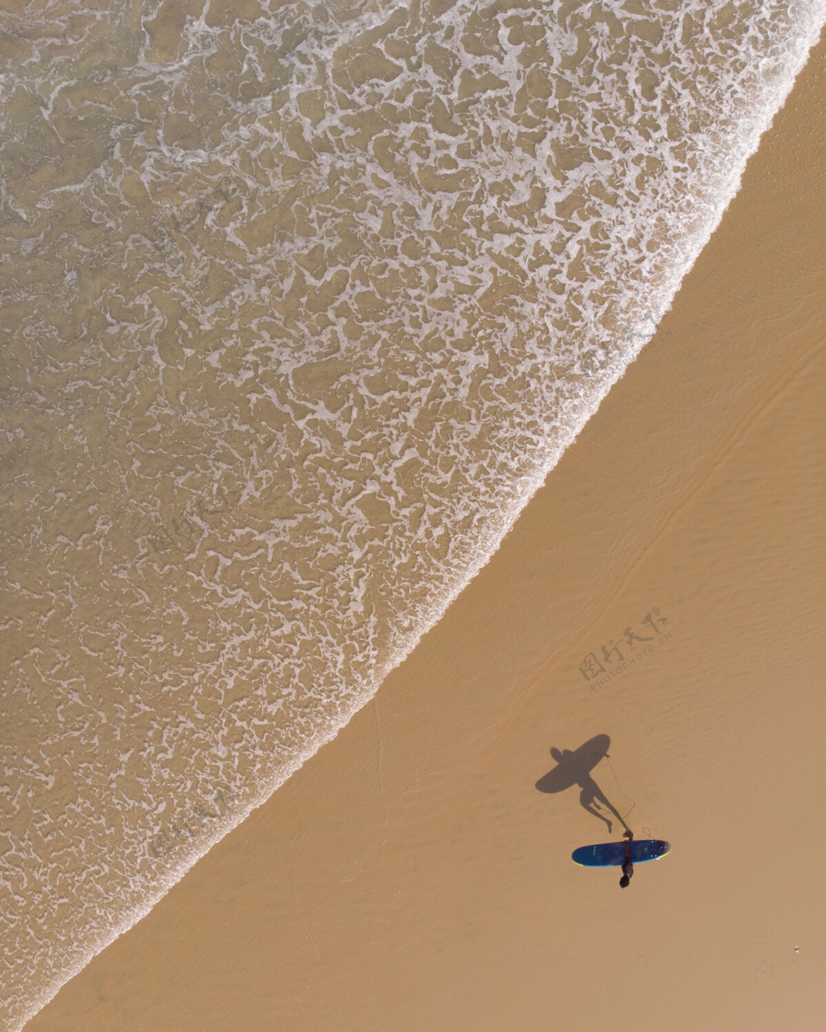 度假村顶视图拍摄一个人与冲浪板走在瓦尔卡拉海滩人海滩海洋