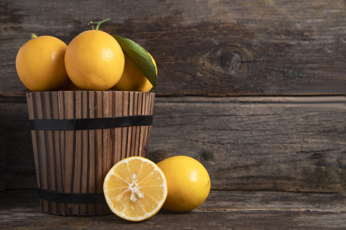 有机一个木制的篮子里装满了新鲜的柠檬水果 叶子放在一张木制的桌子上高质量的照片柠檬柑橘异国情调