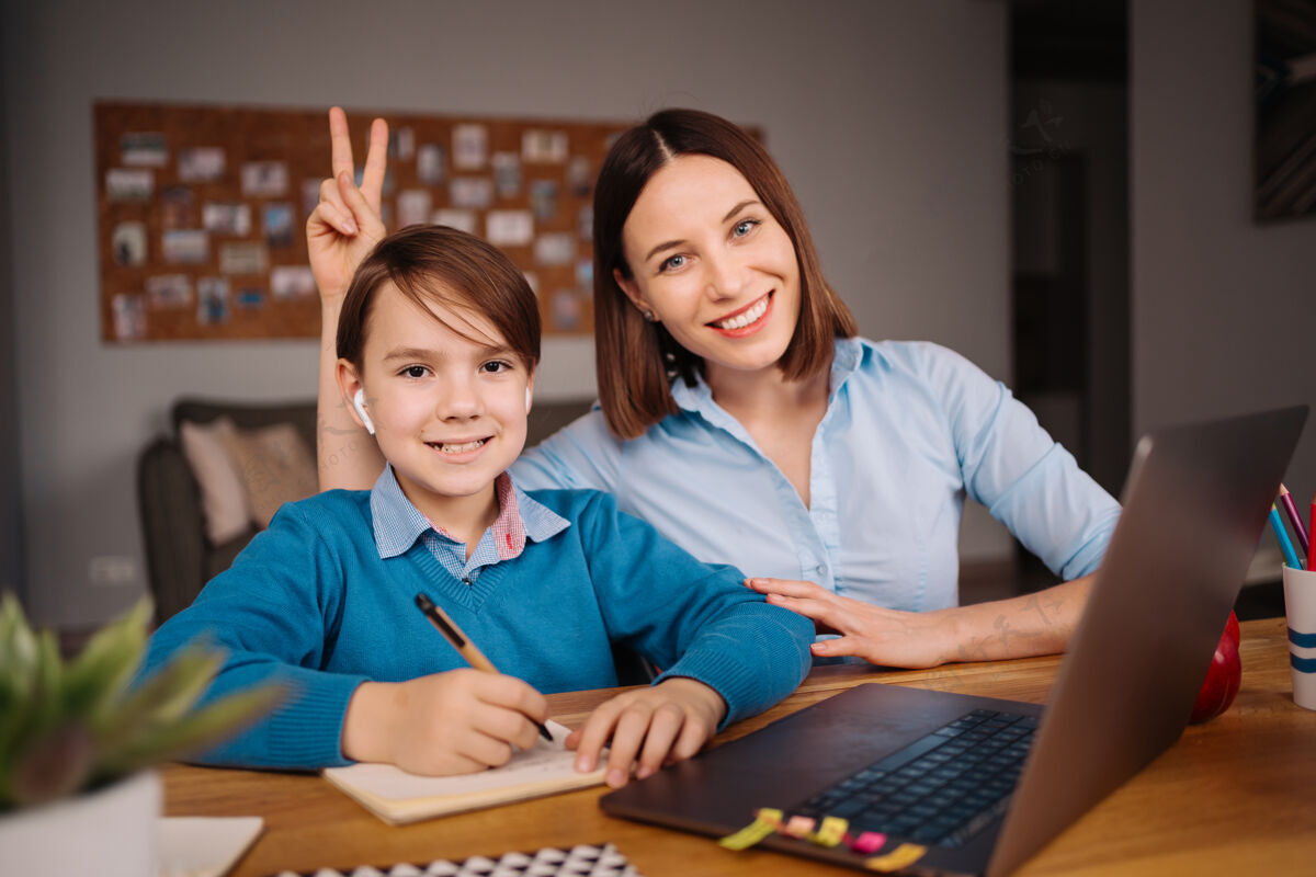 微笑一个未成年男孩用笔记本电脑和他妈妈旁边的老师打视频电话学习在线视频通话