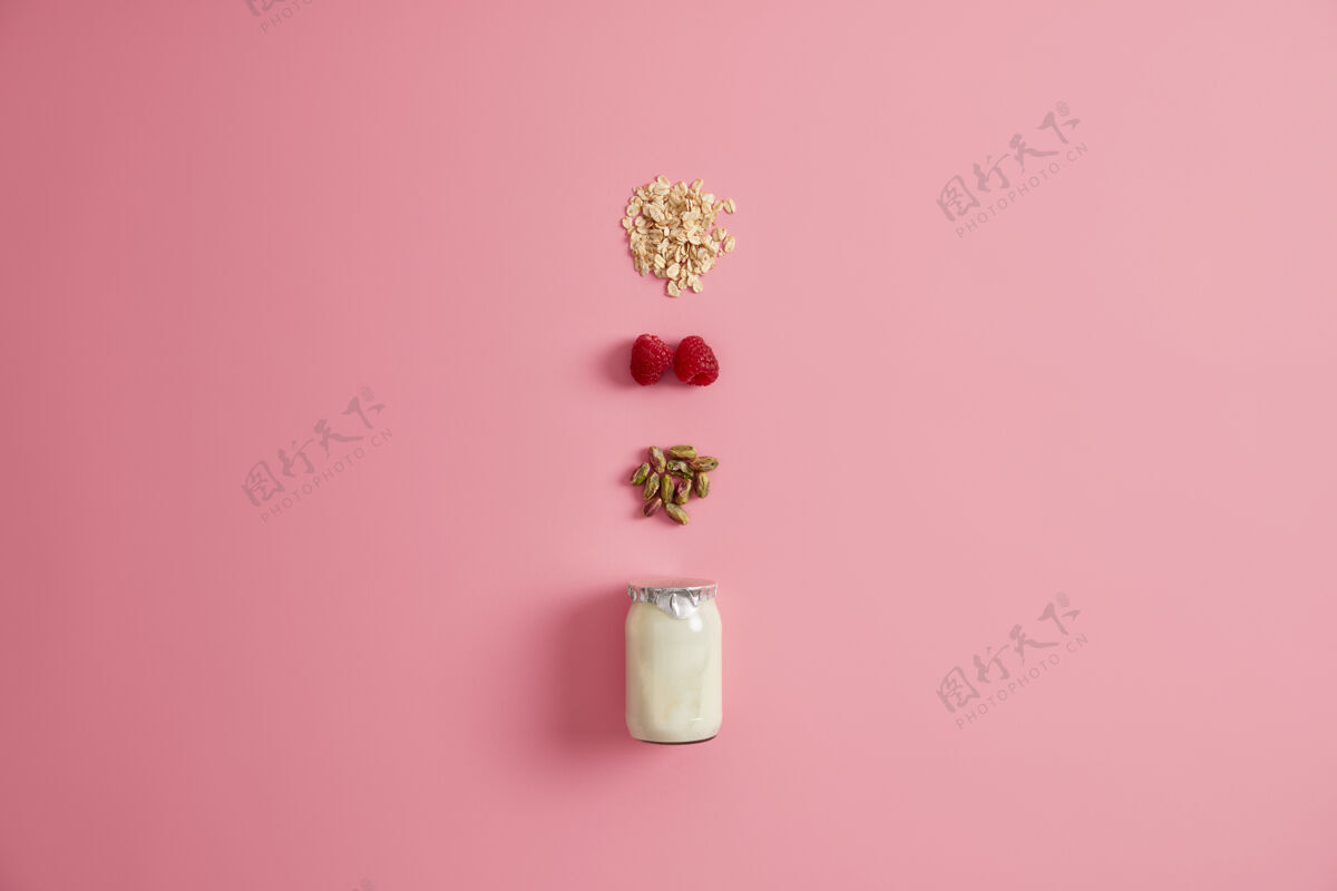 物品玻璃罐酸奶 开心果 红莓和谷类混合在一起吃粉红色背景健康饮食早餐粥或快餐的天然原料素食餐燕麦种子饮食