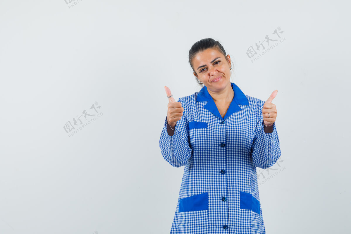 睡衣穿着蓝色方格布睡衣的年轻女子竖起大拇指 看起来很漂亮 正面视图成人女性模特