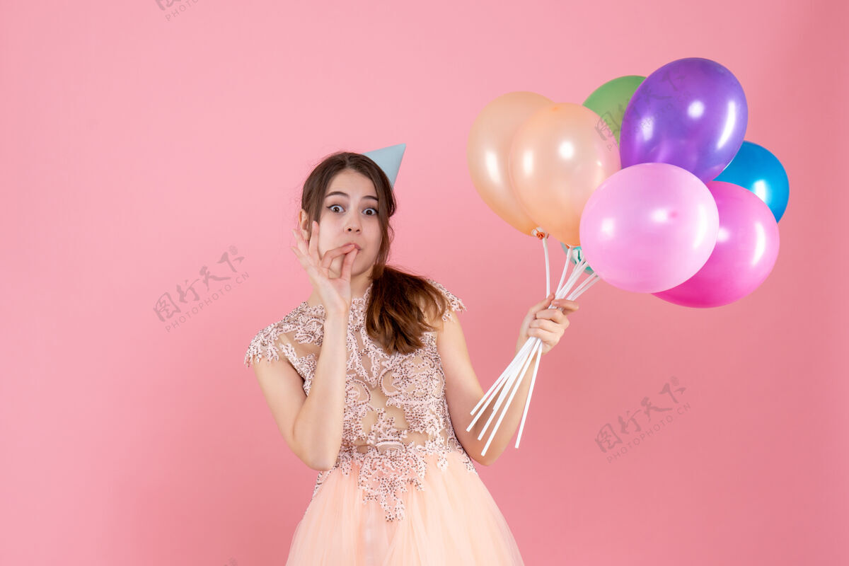 生日正面图可爱的女孩戴着派对帽拿着气球做美味的招牌派对粉色可爱的女孩