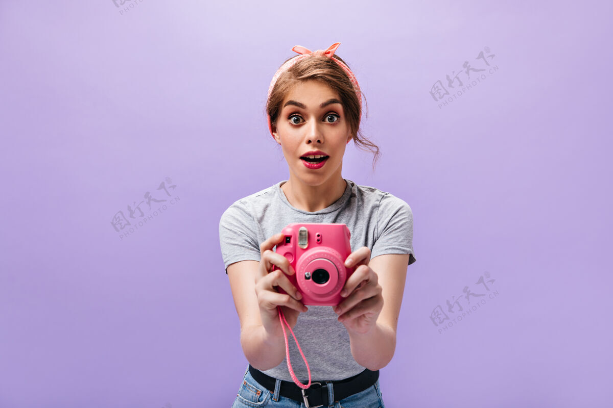 表情这位女士看起来很惊讶 用粉色相机拍照穿着灰色t恤 红润嘴唇的时髦年轻女子摆姿势年轻姿势女人