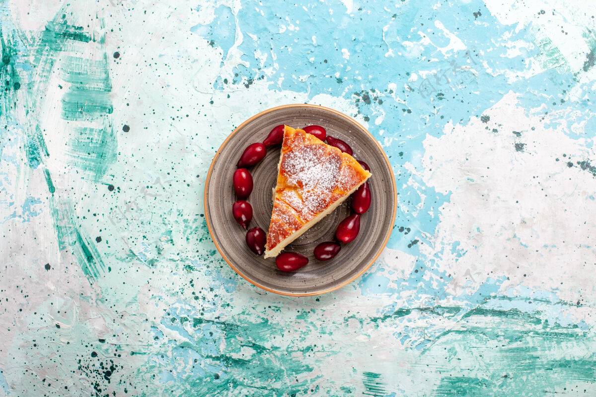 顶部顶视图蛋糕片与新鲜的红山茱萸在淡蓝色的表面水果蛋糕烤派糖饼干甜山茱萸蛋糕光