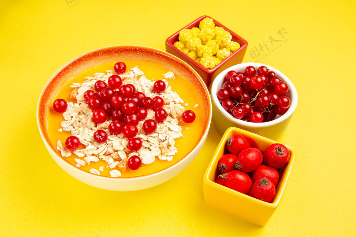 甜点侧面特写镜头：黄色桌子上有浆果 浆果 糖果 燕麦片和红醋栗新鲜燕麦片红葡萄干