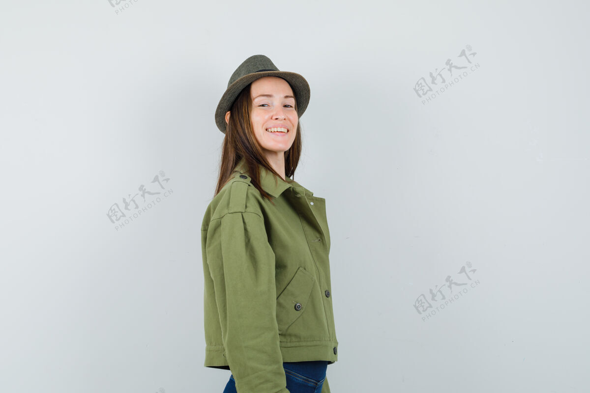 夹克年轻的女士看着相机穿着夹克裤子帽子 看起来很迷人深色魅力优雅
