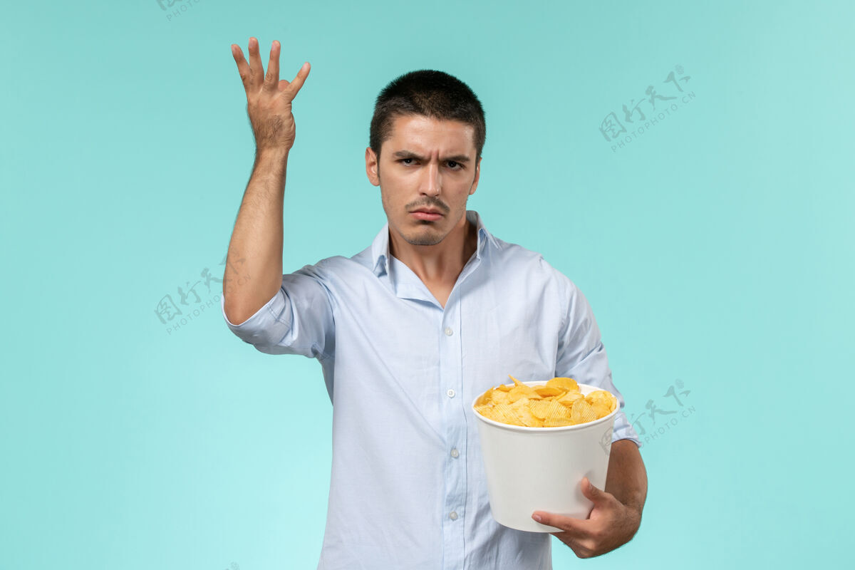 土豆正面图年轻人拿着篮子和土豆在浅蓝的墙上吃着看电影孤独的遥远的电影院男人成人篮子