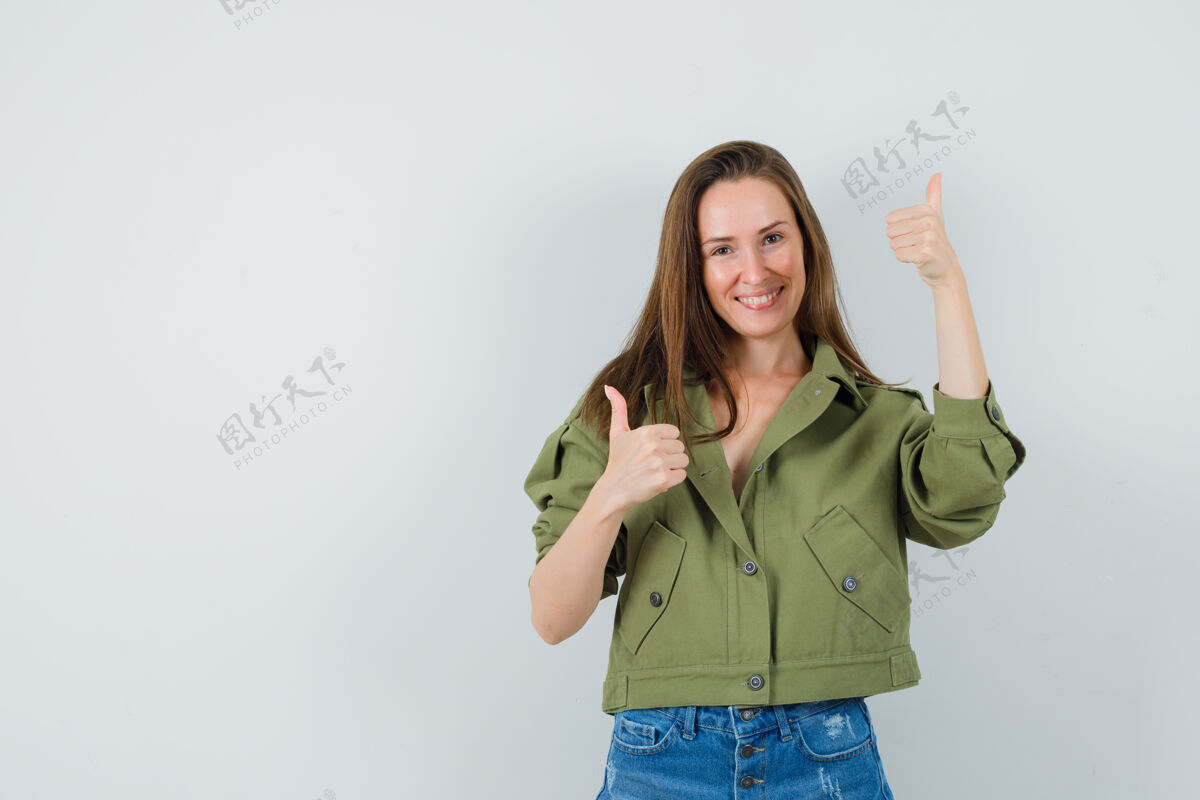 拇指穿着绿色夹克短裤的年轻女士竖起大拇指 看起来很高兴双人床欢快休闲