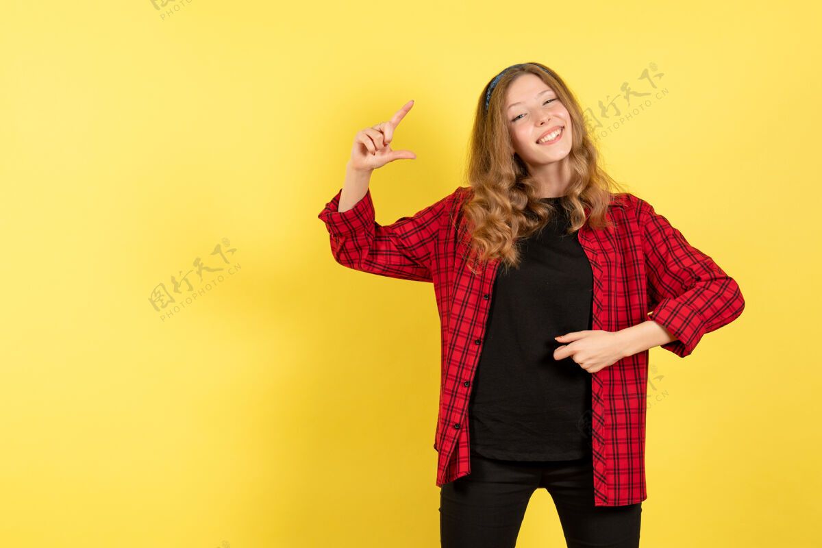 漂亮正面图穿着红色格子衬衫的年轻女性在黄色背景上微笑着摆姿势人类女孩情感色彩模特女人微笑格子衬衫