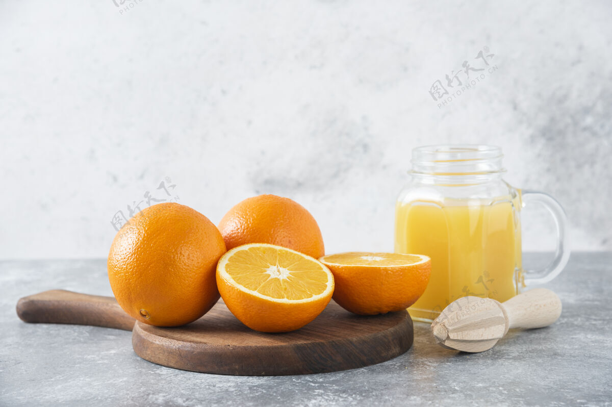 热带石桌上放着一杯果汁和新鲜的橙子异国情调橙子天然