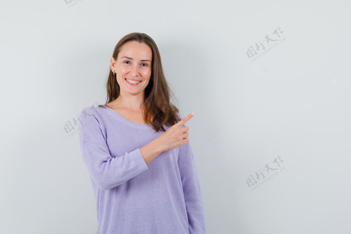 靠边年轻的女人一边指着一边笑着 一边穿着淡紫色的衬衫 看上去很高兴优雅化妆漂亮