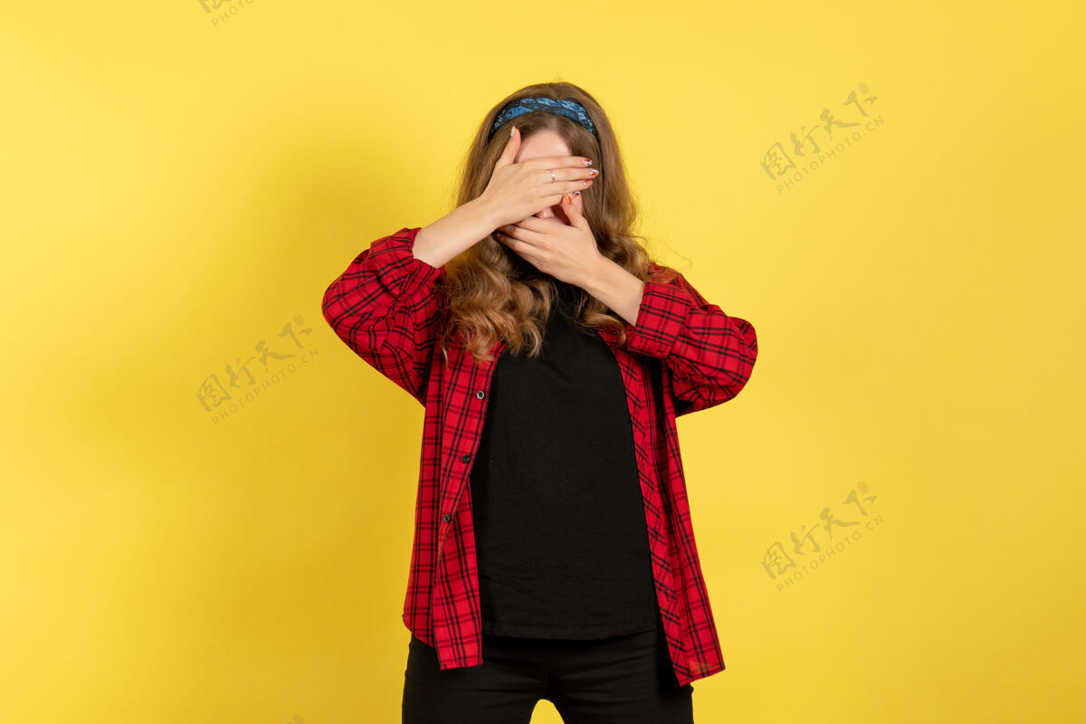 人类正面图穿着红色格子衬衫的年轻女性在黄色背景上遮住脸摆姿势模特女孩女人颜色情感人类女性衬衫女性女孩