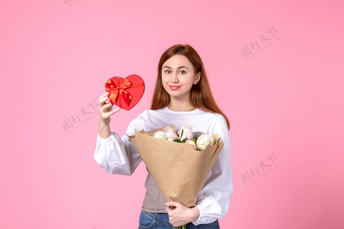 年轻女性正面图：年轻女性 带鲜花 在粉色背景上作为妇女节礼物 水平三月女性平等性感女性约会玫瑰人礼物玫瑰