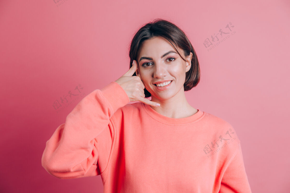 女人背景上穿着休闲毛衣的女人微笑着用手和手指做电话手势 就像在打电话表情手正面