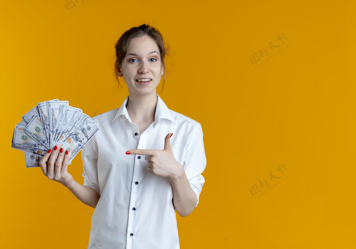 惊喜年轻惊讶的金发俄罗斯女孩拿着 指着橘子上的钱和复制空间金发年轻持有