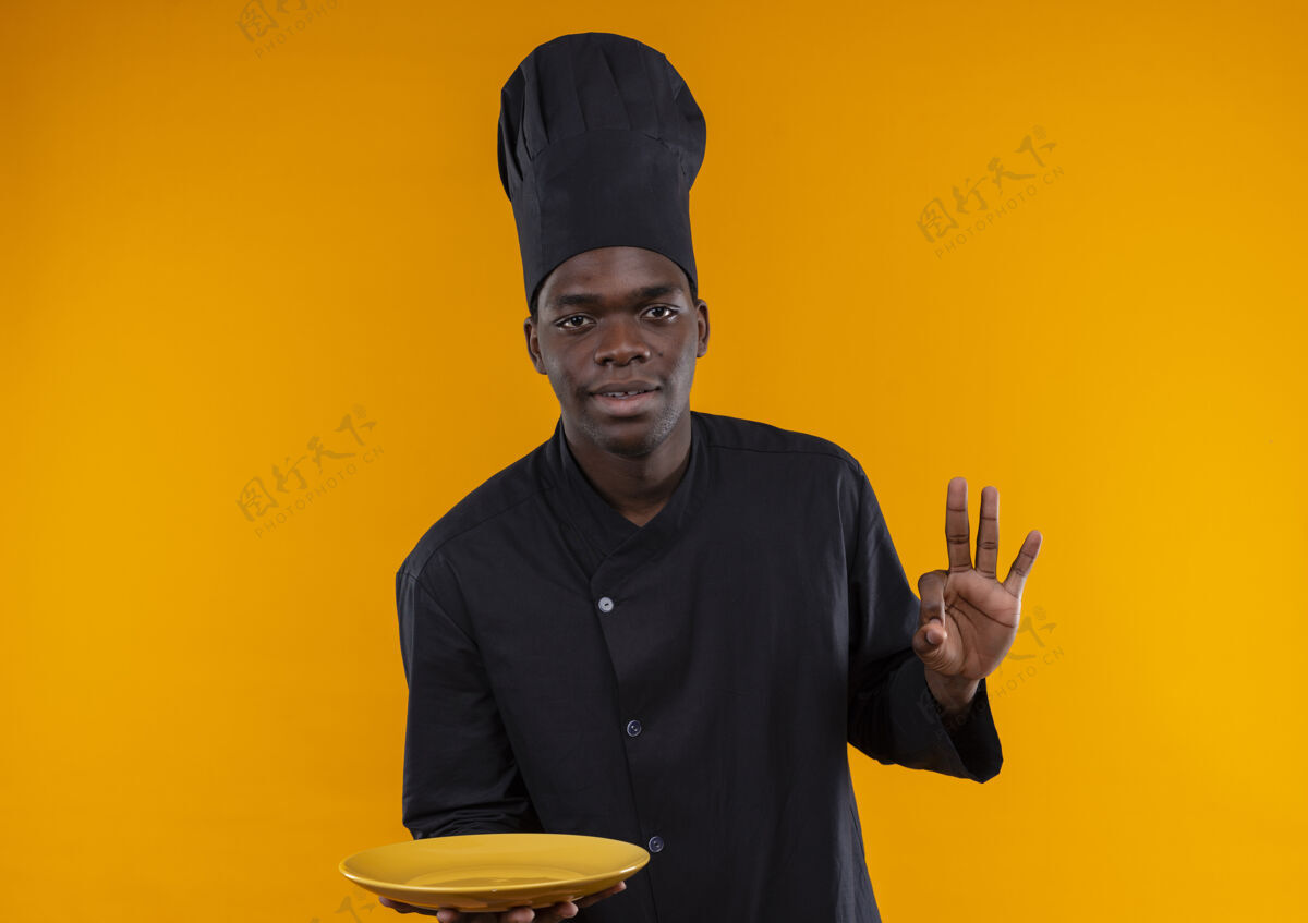 盘子年轻的美籍黑人厨师身着厨师制服 拿着盘子 在橘子上做手势 并留有空白非裔美国人空间年轻