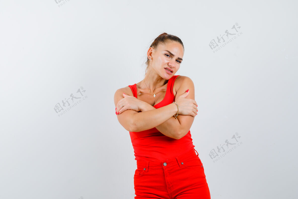 专注穿着红色单品 红色裤子的年轻女士 拥抱着自己 看起来很专注 正面视图皮肤干净年轻