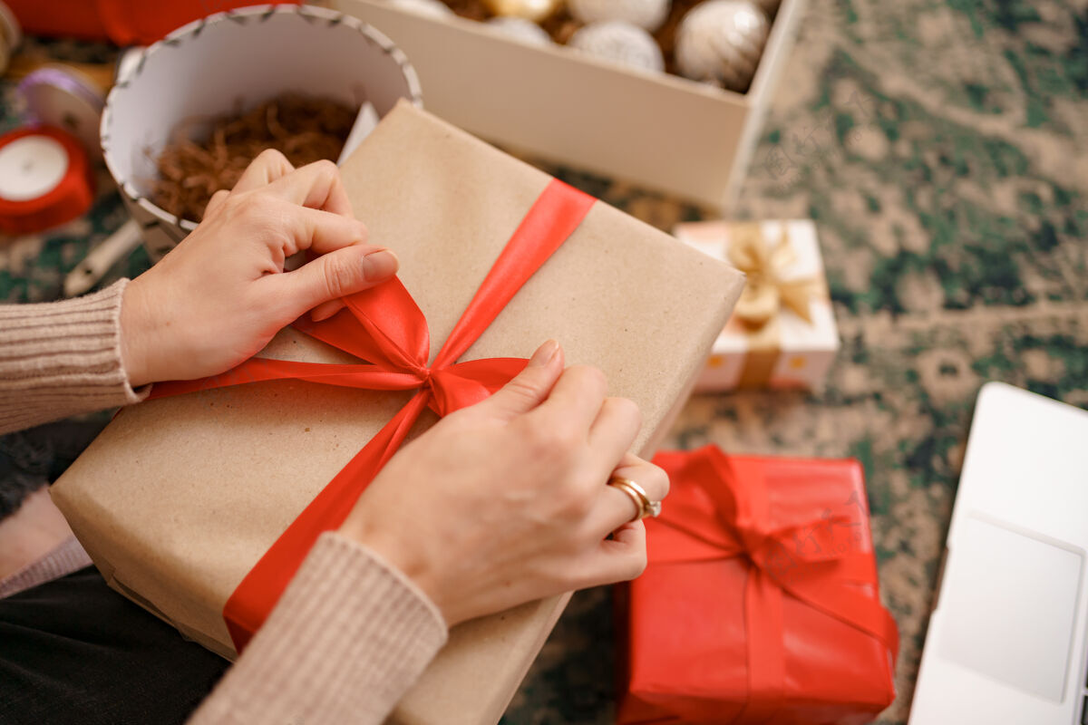 女性近距离的女性手绑在一个工艺礼品盒红丝带蝴蝶结包装经典盒子