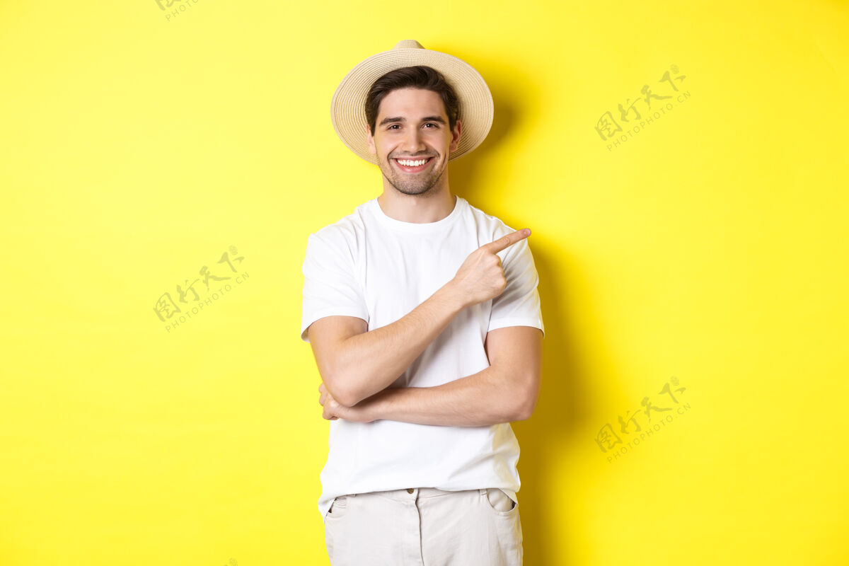 模特年轻男性游客右手指 微笑着展示广告 旅游理念和生活方式 黄色背景男人夏天年轻