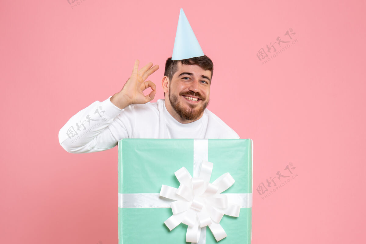 衣服正面图：年轻男性站在礼物盒内 参加粉色照片颜色的圣诞睡衣派对颜色帽子帽子