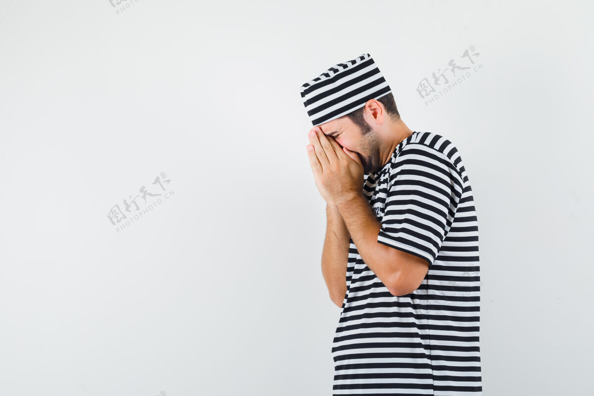 男人年轻男子手捂着脸 穿着t恤衫 戴着帽子哭泣 看上去很悲伤人男人衬衫