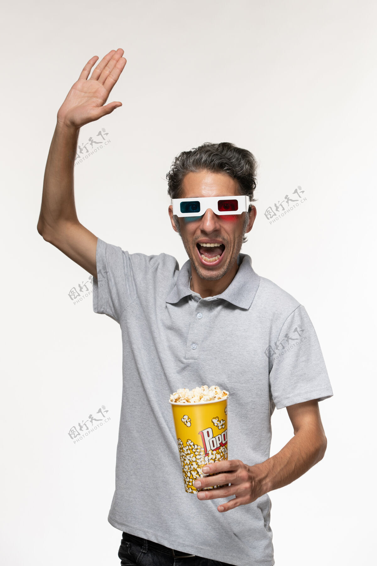 正面正面图年轻男性手持爆米花包 戴着d型太阳镜 表面呈浅白色爆米花电影遥控