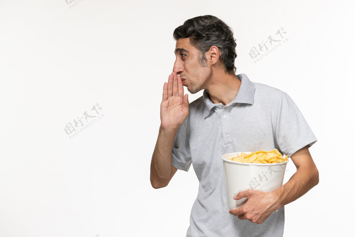 服务员正面图：年轻的男性拿着一个装着薯片的篮子 在一个白色的表面上与人交谈孤独年轻的男电影