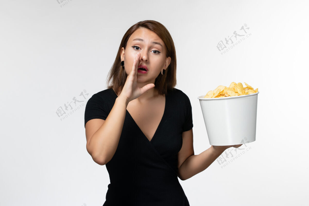 举行正面图身穿黑色衬衫的年轻女性手持薯片在白色表面低语电影院电影动画
