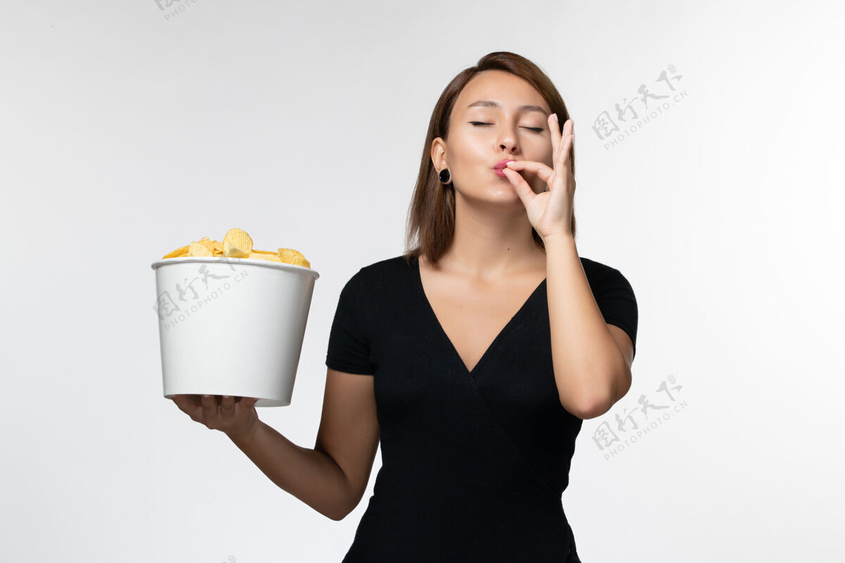 女商人正面图：年轻女性拿着土豆片篮子 在浅白的桌子上摆姿势浅白色电影年轻女性